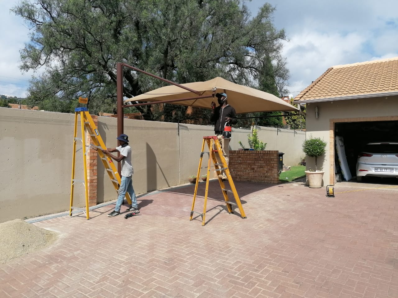 Protect A Dome installers fitting a beige residential shadeport